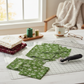 Winter Solstice II Green Snowflakes Metallic quilting cotton by Jason Yenter for In The Beginning Fabrics — fabric cut into squares alongside coordinating burgundy snowflake and cream celestial metallic fabrics in a holiday quilt in progress, with cutting mat and rotary cutter in a cozy workspace. Quilts shown for inspiration. Coordinating fabrics and quilt patterns are available at IraRobi Quilts.