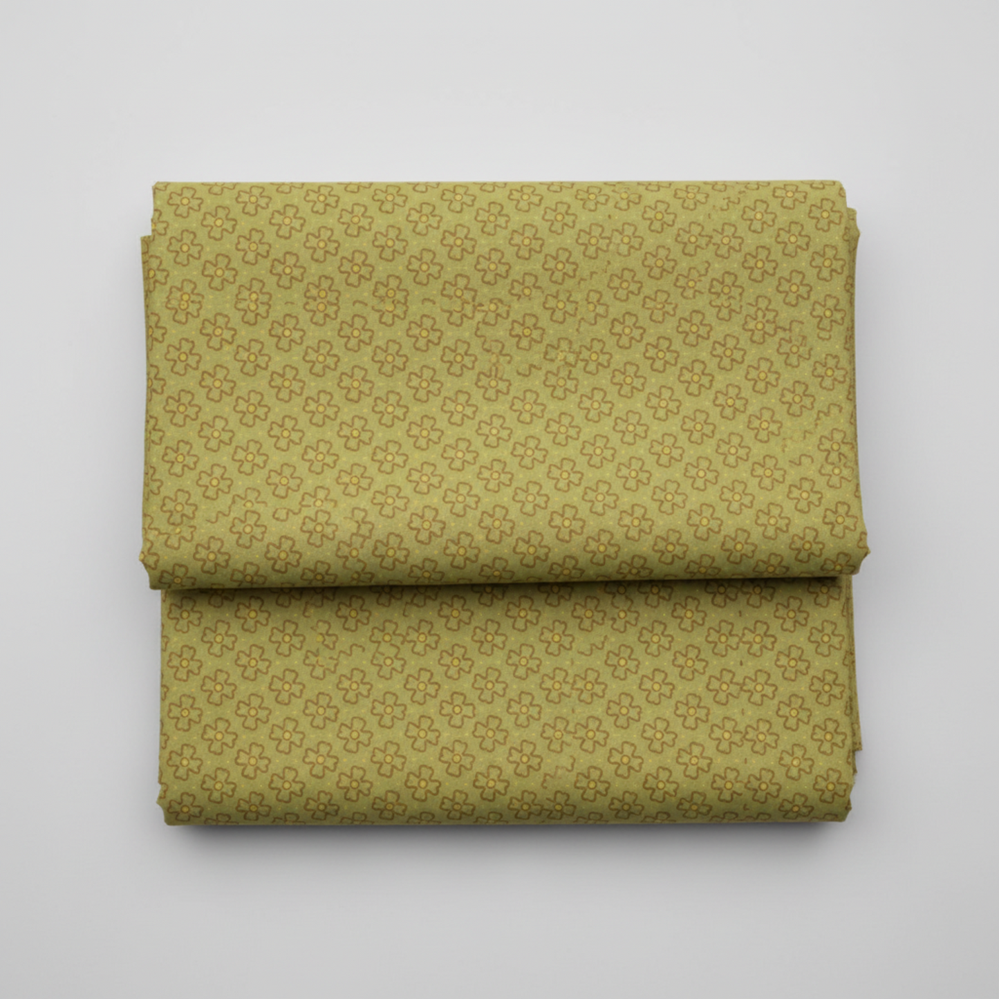 Golden Era by Paula Barnes, Wavy Daisy Green quilting cotton for Marcus Fabrics — neatly folded fabric showing soft sage-olive green ground with all-over tossed wavy-outline daisy motif in brown-taupe with yellow-gold centers, 100% cotton 43–44" wide