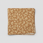 Front Porch by Dolores Smith, Swing Rust quilting cotton for Marcus Fabrics — neatly folded fabric showing warm rust-amber ground with all-over tossed scrolling acanthus and oak leaf motif in cream and gold, 100% cotton 43–44" wide