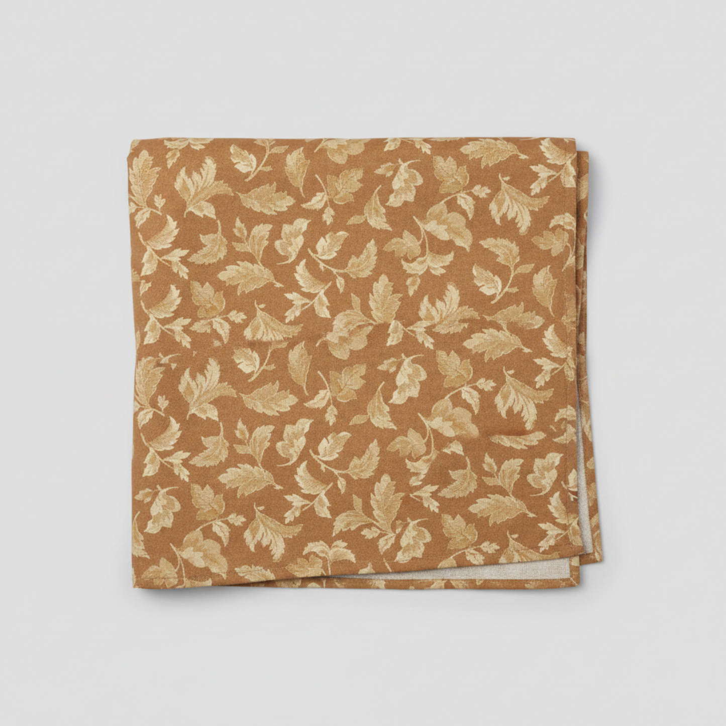 Front Porch by Dolores Smith, Swing Rust quilting cotton for Marcus Fabrics — neatly folded fabric showing warm rust-amber ground with all-over tossed scrolling acanthus and oak leaf motif in cream and gold, 100% cotton 43–44" wide