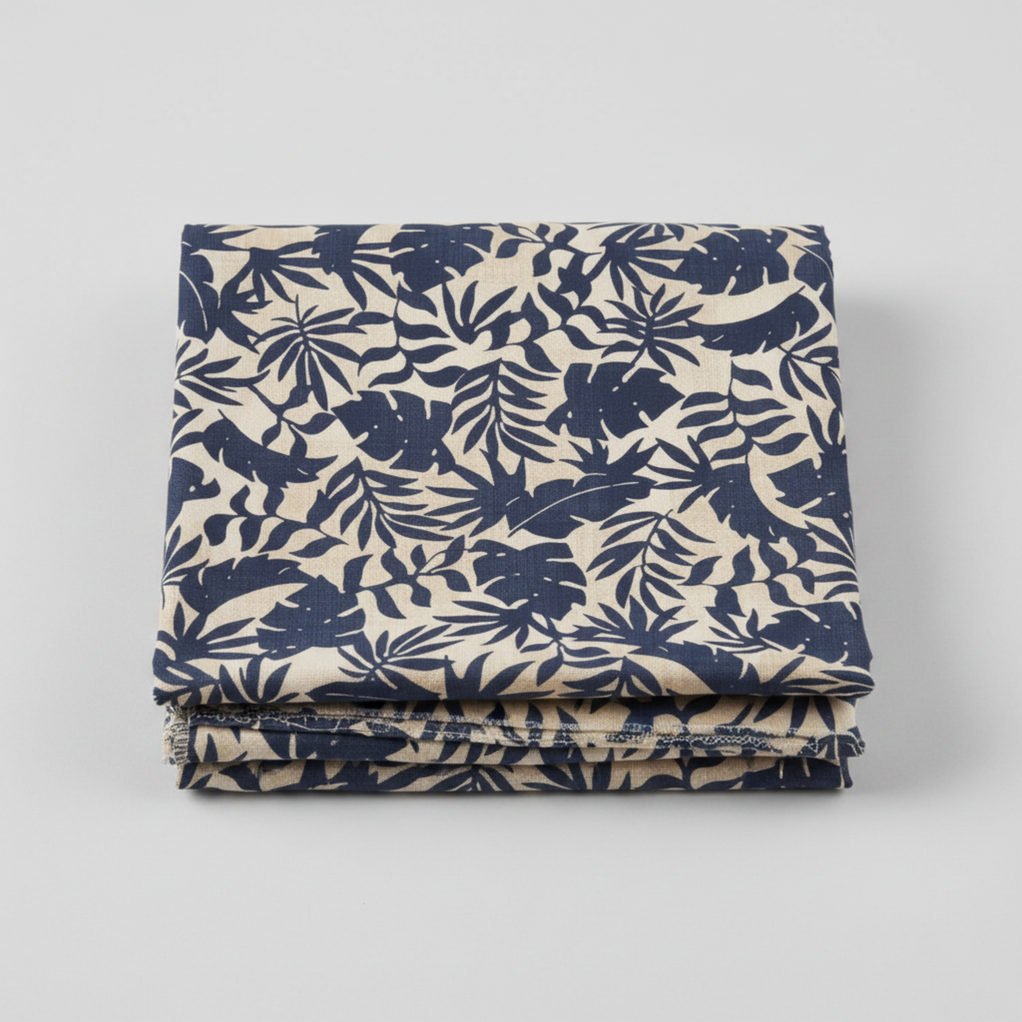 Breezeway by Maywood Studio, Textured Palms Blue/Cream quilting cotton — neatly folded fabric showing warm cream ground with bold navy-blue silhouette tropical palm fronds and monstera leaves, 100% cotton 43–44" wide