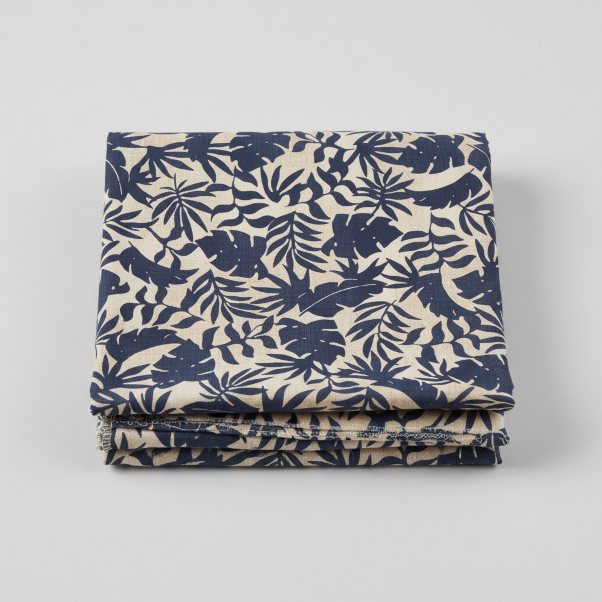 Breezeway by Maywood Studio, Textured Palms Blue/Cream quilting cotton — neatly folded fabric showing warm cream ground with bold navy-blue silhouette tropical palm fronds and monstera leaves, 100% cotton 43–44" wide