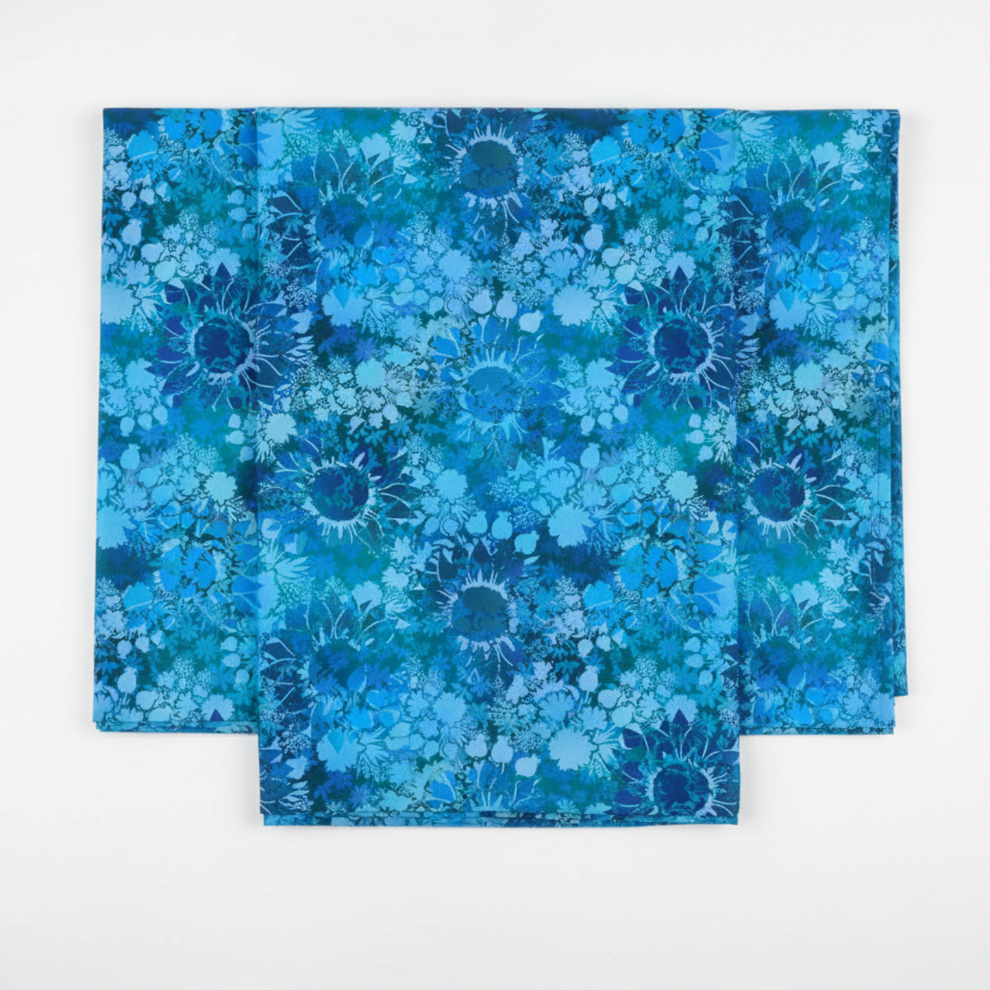 I Dream In Color Sunflower Blue quilting cotton fabric folded to show allover tonal shadow floral – silhouetted sunflowers, daisy clusters, berry sprigs, and leaves in vibrant cobalt, cerulean, teal, and deep navy watercolor wash by Jason Yenter for In The Beginning Fabrics, 100% cotton, 3 yard cut