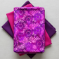 I Dream In Color Sunflower Magenta fabric by Jason Yenter for In The Beginning Fabrics folded on a light linen surface with coordinating jewel-toned pink and purple fabrics – dense allover tonal shadow floral with silhouetted sunflowers and daisy clusters in magenta, hot pink, fuchsia, and deep purple watercolor wash, 100% cotton, 3 yard cut