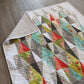 Harlequin quilt pattern by Robin Pickens – full quilt with colorful diamond design displayed on a wooden floor
