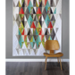 Harlequin quilt pattern by Robin Pickens – colorful geometric diamond quilt displayed on a wall with wooden chair