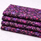 Halcyon II Magenta Vines fabric stacked in four folded cuts showing small pink, magenta, and blue floral print on deep purple-black cotton by Jason Yenter for In The Beginning Fabrics