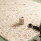 Halcyon II Multi Cream Roses quilting cotton on cutting mat with rotary cutter, thread, and sewing machine by Jason Yenter for In The Beginning Fabrics