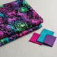 Impressions Jewel Jungle fabric by Jason Yenter for In The Beginning Fabrics folded on a linen surface – jewel-toned animal silhouettes and lush botanical foliage in hot pink, purple, teal, and lime green on deep black ground, perfect for bold and dramatic quilt projects, 100% cotton, 3 yard cut