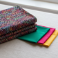 Impressions Multi Dark Raindrops fabric by Jason Yenter for In The Beginning Fabrics folded on a linen surface – dense multicolor teardrop pattern in jewel tones of red, pink, teal, green, and yellow on deep dark ground, perfect for scrappy and blender quilt projects, 100% cotton, 3 yard cut