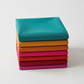 Interwoven Blue Green Fabric by Jason Yenter for In The Beginning Fabrics on top of a coordinating Interwoven fat quarter stack — vivid teal crosshatch tonal with tomato, butterscotch, hot pink, red, crimson, and orchid tonals below. 100% cotton, 43–44" wide.