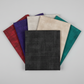 Interwoven Charcoal quilting cotton fabric by Jason Yenter for In The Beginning Fabrics fanned with coordinating Interwoven fabrics in red, blueberry, taupe, and blue-green – bold geometric crosshatch collection stack
