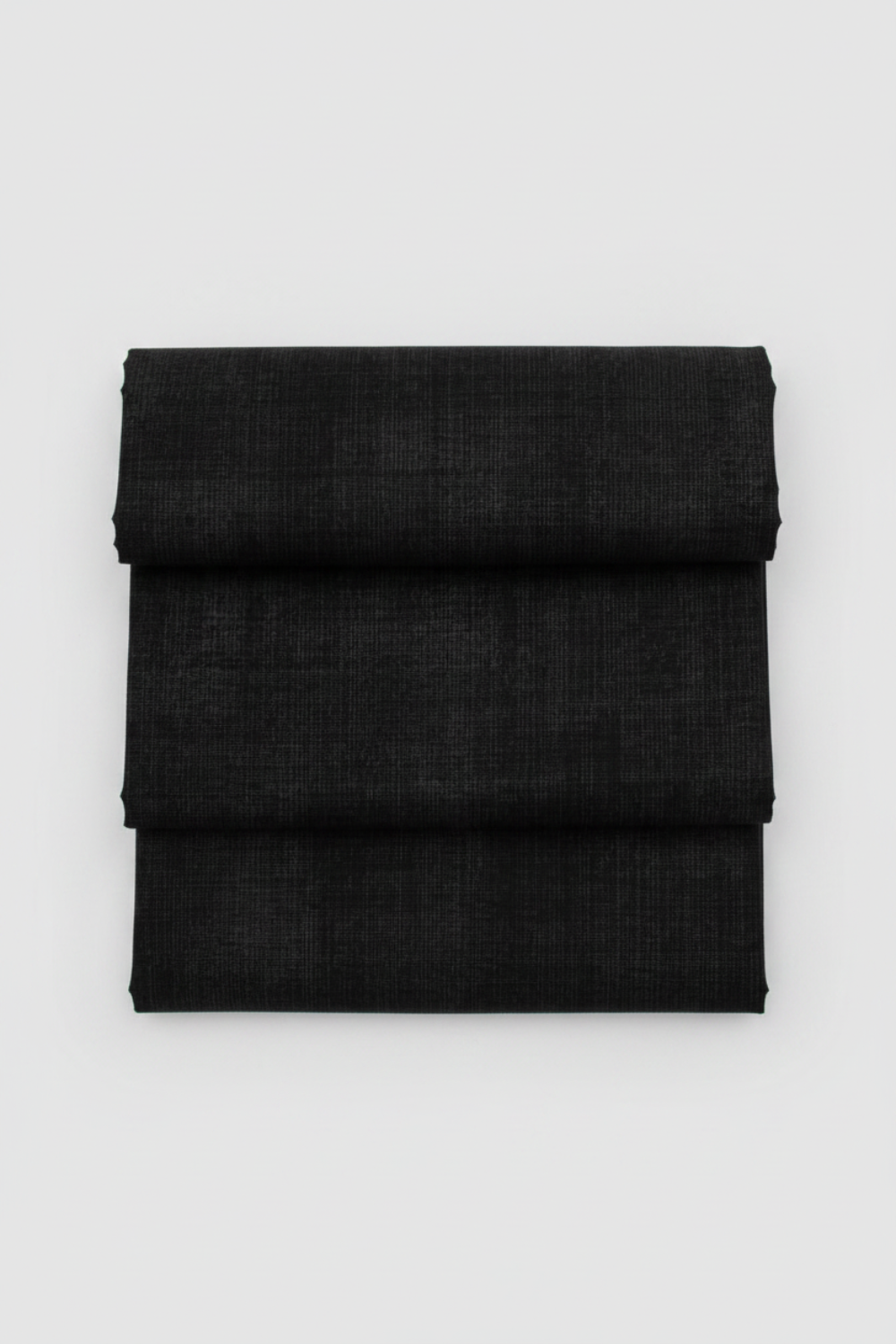 Folded Interwoven Charcoal quilting cotton fabric on a light grey background – by Jason Yenter for In The Beginning Fabrics. Shop at IraRobi Quilts | #charcoalfabric #interwoven #quiltingfabric #neutralfabric #blenderfabric