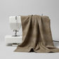 Interwoven Olive quilting cotton fabric draped naturally over a sewing machine with soft folds showing the warm olive-brown geometric crosshatch print – by Jason Yenter for In The Beginning Fabrics