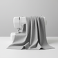 Interwoven Pewter Fabric by Jason Yenter for In The Beginning Fabrics draped over a sewing machine with soft natural folds showing the cool medium grey geometric crosshatch print
