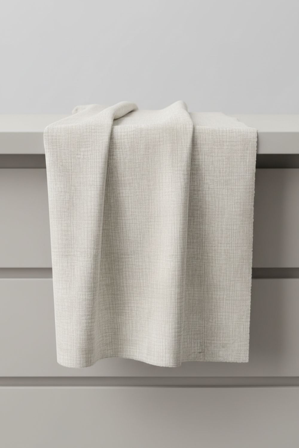 Interwoven Taupe Fabric by Jason Yenter for In The Beginning Fabrics — soft cream and taupe linen-look crosshatch blender quilting cotton draped vertically over a grey table edge in a clean quilting studio, raw cut edges, 100% cotton, 43–44" wide