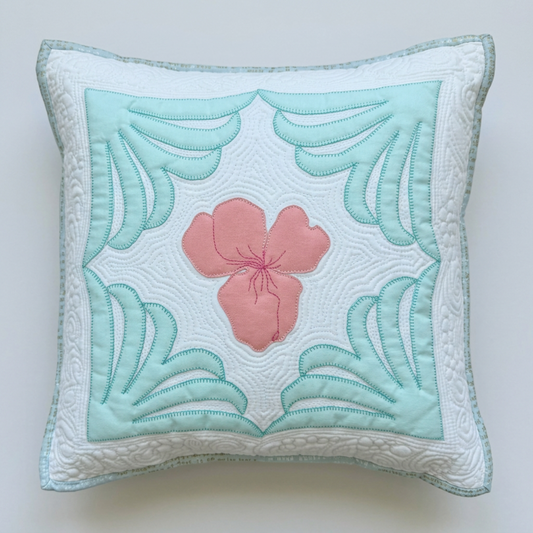 Iris Garden handmade quilted pillow on a light grey background, featuring a blush-pink iris, pale aqua corner motifs, and a white quilted border.