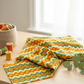 Jungle Friends Multi Stripe 3-yard cut fabric displayed in a bright sewing room, featuring orange, green, yellow, white, and gold geometric stripes.