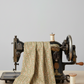 Front Porch by Dolores Smith, Railings Taupe for Marcus Fabrics — taupe-brown quilting cotton with sage green leaf garland stripes draped over a vintage sewing machine, 100% cotton 43–44" wide