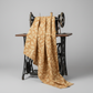 Front Porch Swing Rust quilting cotton by Dolores Smith for Marcus Fabrics — fabric draped over a vintage antique sewing machine showing natural drape and warm rust-amber ground with cream scrolling leaf motif