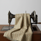 Front Porch Railings Taupe quilting cotton by Dolores Smith for Marcus Fabrics — fabric draped over a vintage antique sewing machine showing natural drape and taupe-brown sage green leaf garland stripe print