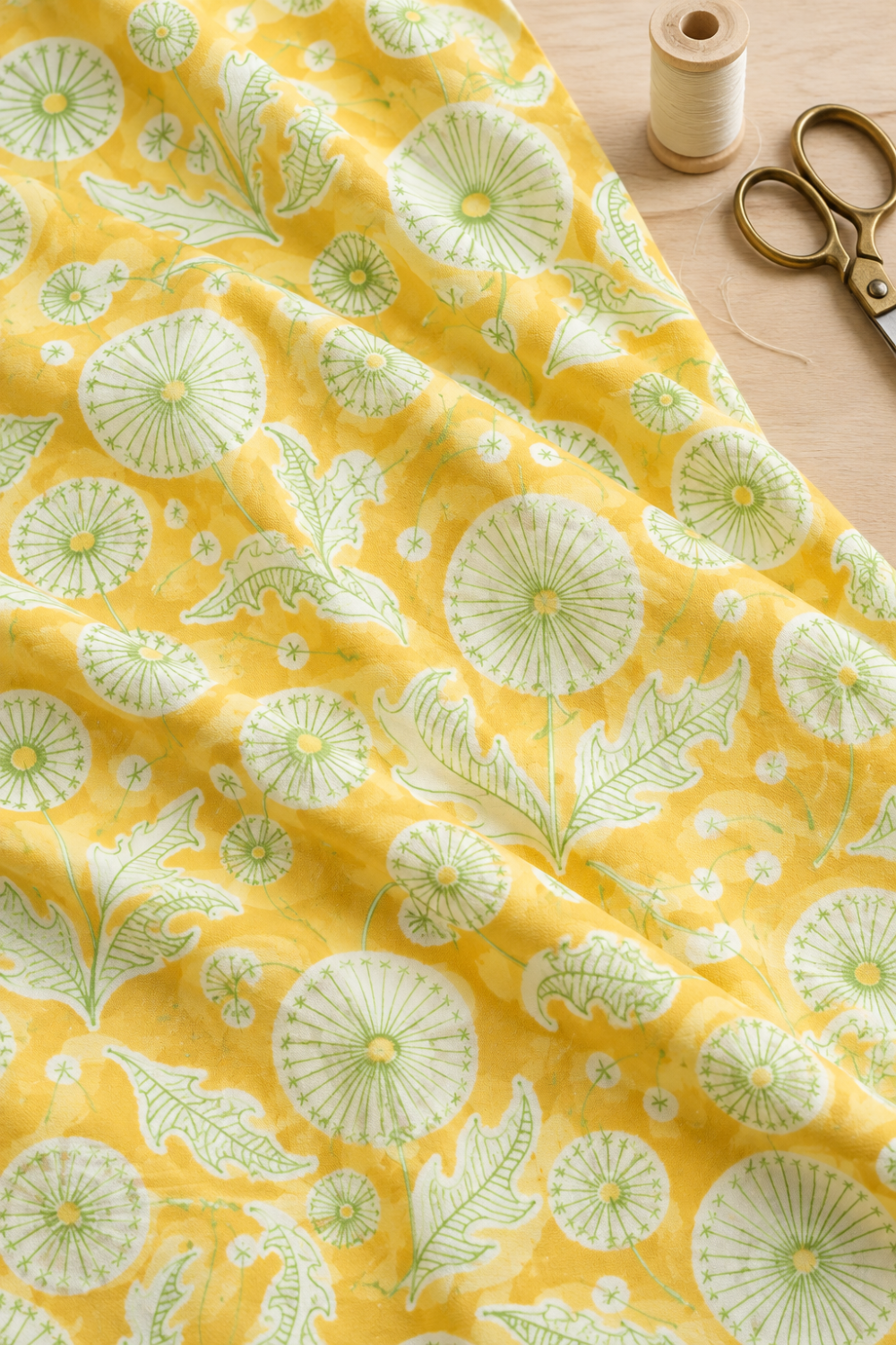 Dandi Duo Dandi Toile Maize fabric draped on a sewing table beside thread and scissors.