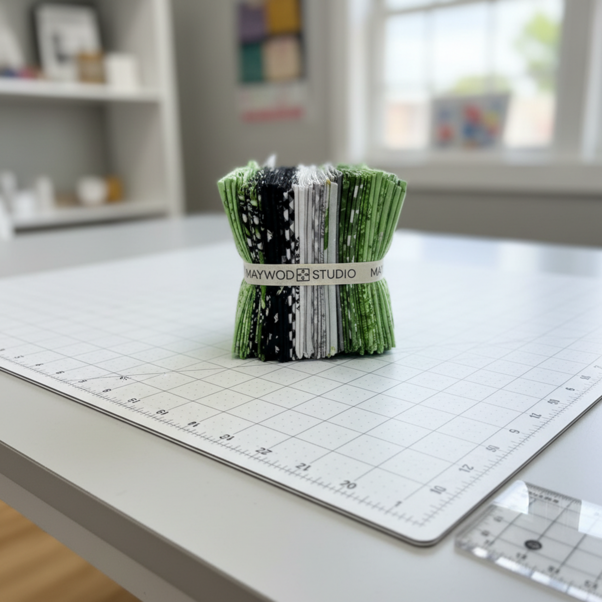 Maywood Studio Greenery Fat Quarter Bundle standing upright on a white cutting mat on a sewing room table