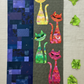 ModCat quilt wall hanging featuring Expressions Batiks Hand-Dyes Shamrock fabric by Riley Blake Designs as the green cat appliqué silhouette and crumpled fabric scraps on the right – bright electric lime-green hand-dyed batik with lively chartreuse yellow and soft teal-blue organic mottled overlays, with yellow, orange-red, and hot pink multicolor batik cat silhouettes on dark olive background, navy indigo patchwork panel, on natural linen. Quilt shown for inspiration features the ModCat Quilt Pattern by Co