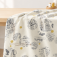 Draped Celestial News Dropping Moonbeam fabric by Zen Chic for Moda Fabrics, with charcoal newsprint motifs and mustard-gold dots on ivory.