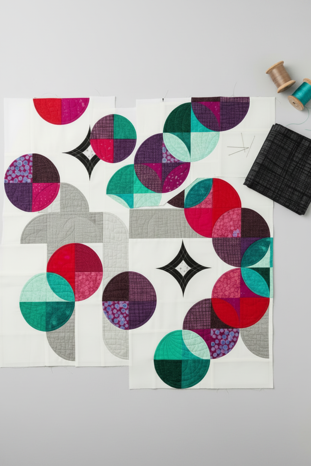 Moondance quilt in progress with Interwoven Charcoal by Jason Yenter for In The Beginning Fabrics – curved petal pieces in deep charcoal, white, teal, magenta and purple with loosely folded fat quarter, pins and thread. Shop Interwoven Charcoal at IraRobi Quilts | #moondance #quiltingfabric #charcoalfabric #interwoven #quiltwip #modernquilt