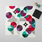 Interwoven Charcoal quilting cotton fabric cut into Moondance curved quilt pieces arranged on a light grey surface with a folded fabric swatch, straight pins, and thread spools – Interwoven Charcoal by Jason Yenter for In The Beginning Fabrics