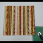 Winter Solstice II Multi Stripe Metallic quilting cotton by Jason Yenter for In The Beginning Fabrics — fabric flat lay showing full Christmas stripe repeat with snowflakes, trees, reindeer, and stars in red, cream, gold, and white with metallic accents, shown with cutting mat and rotary cutter. Quilt blocks shown for inspiration. Coordinating fabrics and quilt patterns are available at IraRobi Quilts.