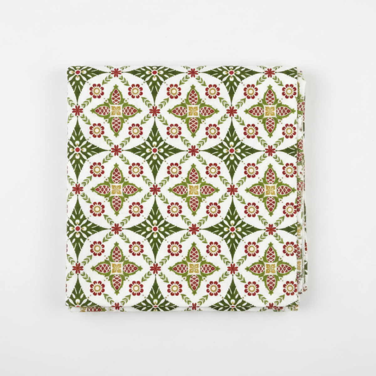 NYSNO New Snow Multicolor Garland quilting cotton by Jason Yenter for In The Beginning Fabrics — folded fat quarter on a white surface showing dense medallion allover with pine cone motifs, red flowers, and olive leaf sprays in forest green, red, and gold on white. Raw cut edges visible. 100% cotton, 43–44" wide.