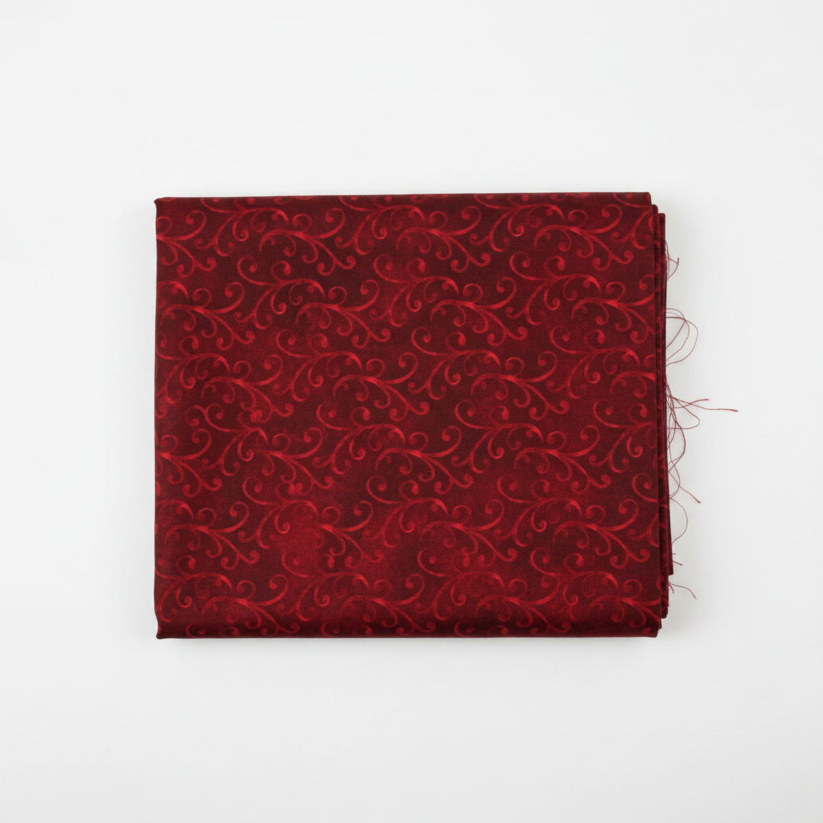 NYSNO New Snow Red Swirl quilting cotton by Jason Yenter for In The Beginning Fabrics — folded fat quarter on a white surface showing dense tone-on-tone crimson scrolls on a richly mottled deep red ground, raw cut edges visible, 100% cotton, 43–44" wide.