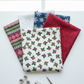 NYSNO New Snow White Holly quilting cotton by Jason Yenter for In The Beginning Fabrics — vertical flat lay as the front hero in a fan of coordinating winter fabrics with silver thread spools and silver scissors on a white surface. Coordinating fabrics and quilt patterns available at IraRobi Quilts.