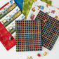 On the Go Plaid Multi quilting cotton by Jason Yenter for In The Beginning Fabrics — vertical Pinterest-style fan spread with the bold rainbow grid on black as the front hero fabric, with a yellow toy bicycle, gold star confetti, and colorful thread spools below. Coordinating fabrics and quilt patterns available at IraRobi Quilts.