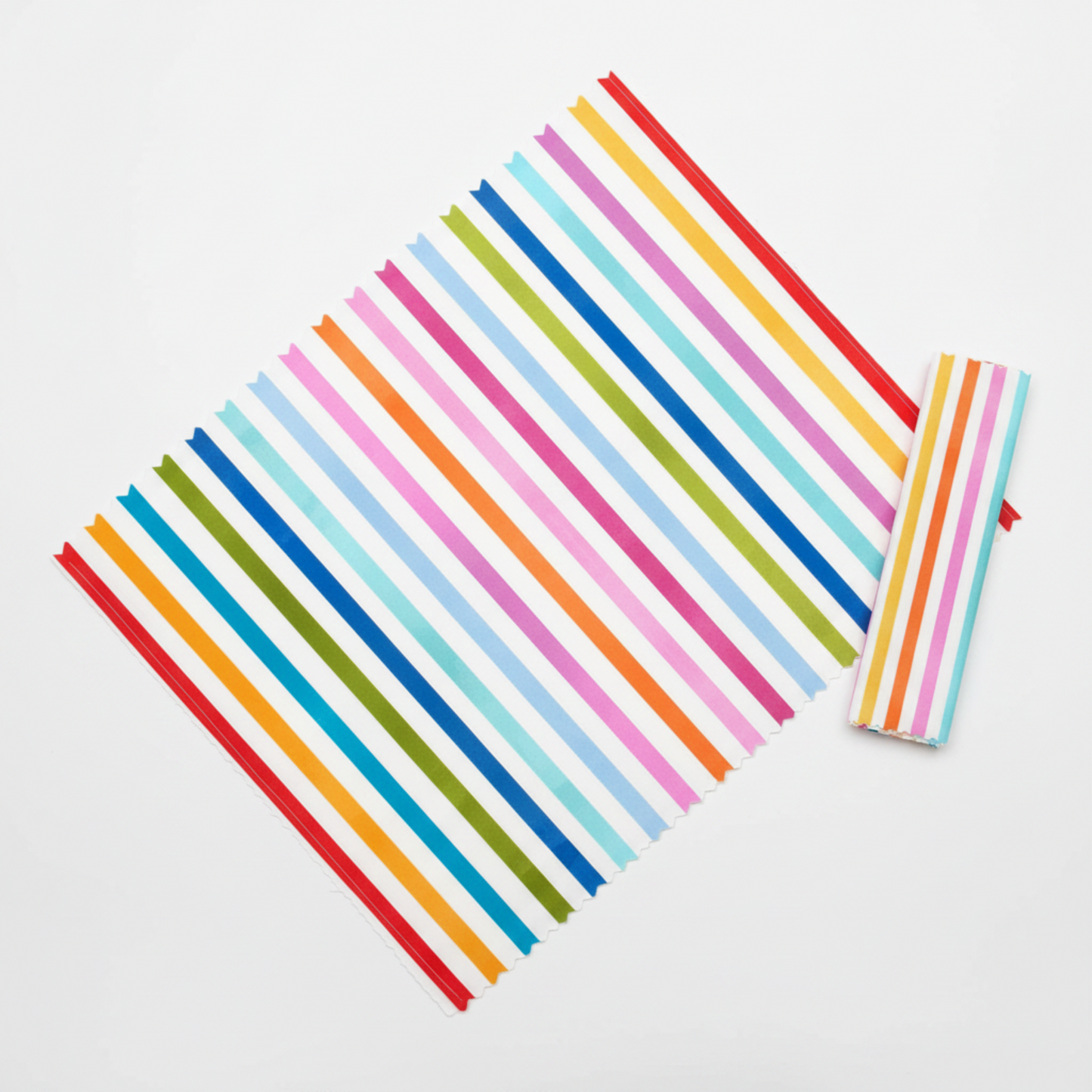 On the Go Stripes Multi quilting cotton by Jason Yenter for In The Beginning Fabrics — flat lay showing fabric cut on the diagonal to demonstrate the dynamic chevron bias effect, with a folded binding strip alongside on a white surface.