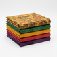 Expressions Batiks Hand-Dyes Orange Multi I fabric by Riley Blake Designs on top of a coordinating stack of five Expressions Batiks Hand-Dyes tonal batik fabrics – complex multicolor amber-orange on top with forest green, curry yellow, tomato red, and deep purple tonal batiks below, 100% cotton
