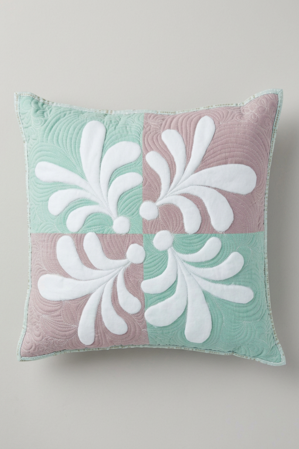 Pastel Harmony quilted pillow with four alternating mint-green and dusty-mauve squares, raised white teardrop motifs, and echo quilting on light grey.