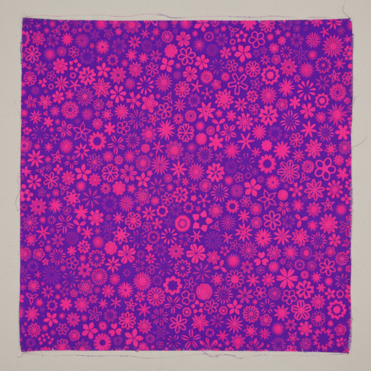PAWsitivity Purple Field quilting cotton by Jason Yenter for In The Beginning Fabrics — close-up flat lay showing dense scattered ditsy floral medley of daisies, sunbursts, four-petal blooms, and cheerful flower silhouettes in vivid magenta-pink and hot pink on rich saturated violet-purple ground, 100% cotton, 43–44" wide.