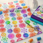 PAWsitivity White Flower Stripe quilting cotton by Jason Yenter for In The Beginning Fabrics — loosely draped on a white wooden surface with coordinating PAWsitivity fabrics in purple, teal, and rainbow tones, rainbow thread spools, gold scissors, and a white ceramic cat figurine. Coordinating fabrics and quilt patterns are available at IraRobi Quilts.