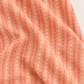 Folded Dandi Duo Peach fabric showing coral stitched-X rows and white starbursts on peach.
