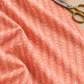 Dandi Duo Peach fabric draped on a sewing table beside a thread spool and scissors.