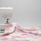 Fire & Ice by Maywood Studio Peach Ice Dye cotton quilting fabric draped over a white sewing machine on light grey background