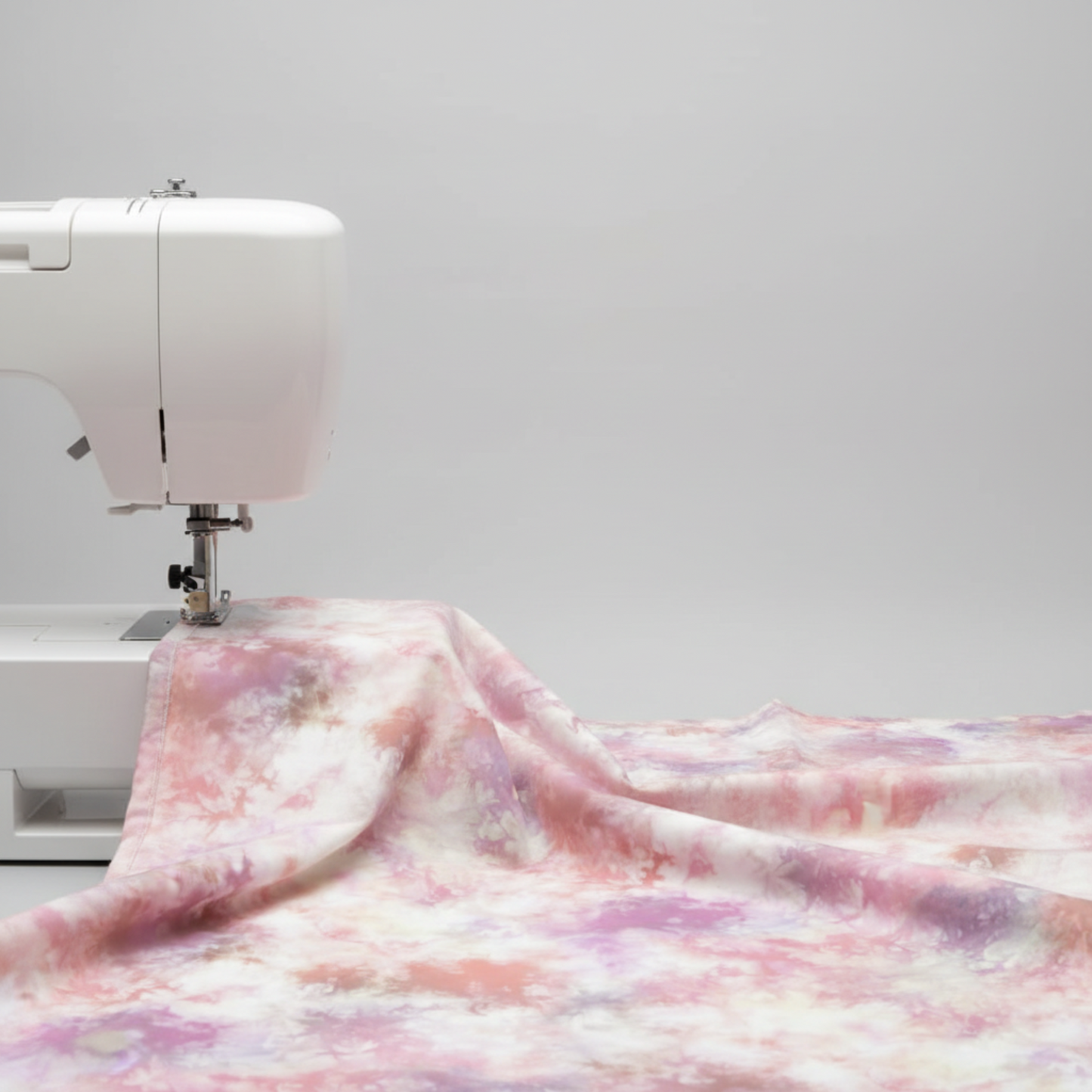 Fire & Ice by Maywood Studio Peach Ice Dye cotton quilting fabric draped over a white sewing machine on light grey background