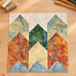 Windsong Block of the Month quilt block by Wing and a Prayer Design, styled on a sewing-room table with coordinating Tonga Batik scraps, thread, clips, a rotary cutter, and thimble. Quilt block and coordinating fabrics are shown for inspiration; patterns are not included with this fabric.