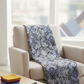 What If Prima Donna Grey/Blue quilting fabric draped over neutral chair in bright quilting studio with coordinating fabric stack and rotary cutter