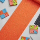 Safari Fun Floating Triangles Orange by Terry Runyan for Benartex – rolled fabric yardage with coordinating Safari Fun quilt blocks, scissors, and cutting mat, overhead view