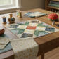 Quilt block featuring Garden of Dreams II Gold Buds 3-yard cut fabric in several pieced sections, with matching folded fabric, thread spools, pins, and fabric remnants on a sewing-room table. Quilt blocks shown for inspiration. Coordinating fabrics and quilt patterns are available at IraRobi Quilts.