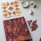 Unfinished star quilt block in cream, gold, brown, and pale blue beside folded Poppy Seeds Raisin fabric, remnants, pins, thread spools, and a sewing machine. Quilt blocks shown for inspiration. Coordinating fabrics and quilt patterns are available at IraRobi Quilts.